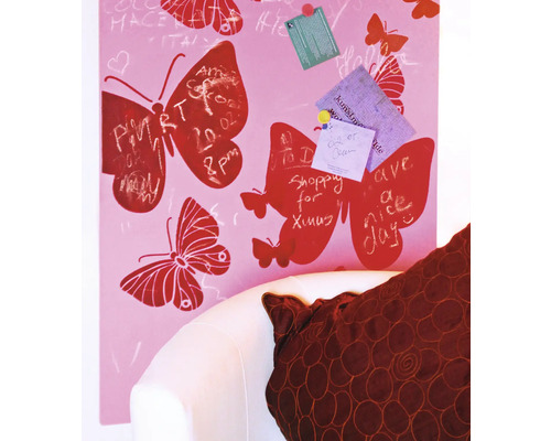 Eine rosafarbene Notiztafel mit Schmetterlingsmotiven und Notizen, die an einer weißen Couch lehnt.