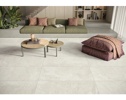 Innenraum mit Bodenfliesen, Couch und Couchtischen.