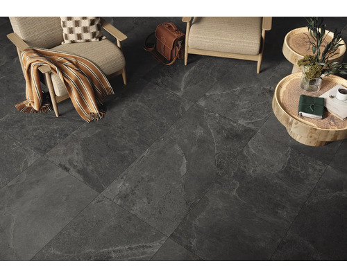 Dunkle Bodenfliesen in einem Wohnzimmer mit Stühlen und Beistelltischen.