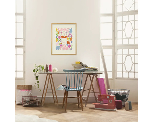 Helles Zimmer mit einem Schreibtisch, an dem eine Nähmaschine und ein Winnie Puuh-Bild stehen.
