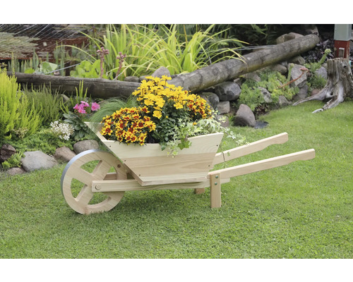 Dekorative Holzschubkarre mit Blumen bepflanzt im Garten.