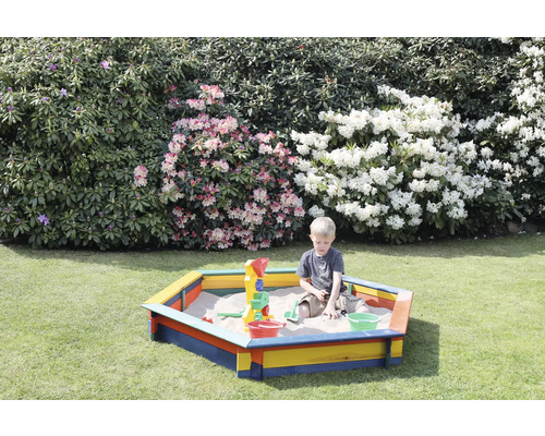 Junge spielt im Sandkasten mit Sandspielzeug im Garten