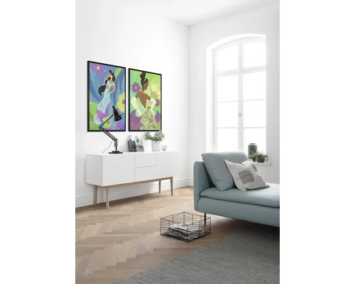 Heller Raum mit zwei gerahmten Wandbildern, einer Kommode, einer Lampe, einer Couch, einem Korb und einem Teppich.