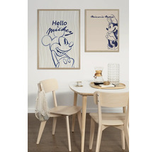 Salle à manger avec table et chaises en bois sous des affiches encadrées de Mickey Mouse et Minnie Mouse