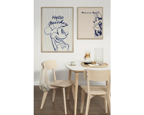 Salle à manger avec table et chaises en bois sous des affiches encadrées de Mickey Mouse et Minnie Mouse