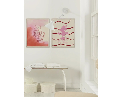 Wanddekoration mit zwei gerahmten Disney-Motiven, Tisch und Lampe in einem hellen Raum