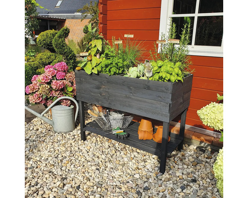 Jardinière sur pieds en bois avec herbes aromatiques et accessoires de jardin dans le jardin
