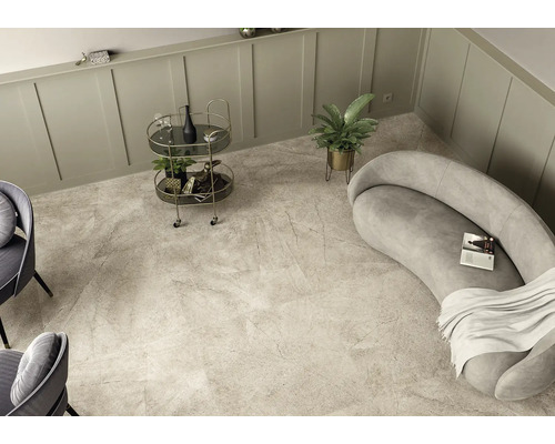 Pièce lumineuse avec carrelage imitation marbre, canapé, chariot de bar et plante d''intérieur.