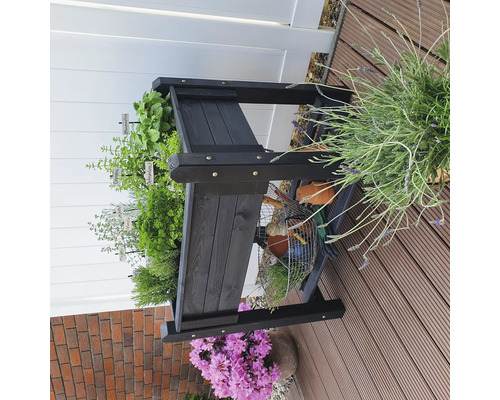 Étagère à herbes aromatiques en bois noir avec diverses herbes et outils de jardin sur une terrasse