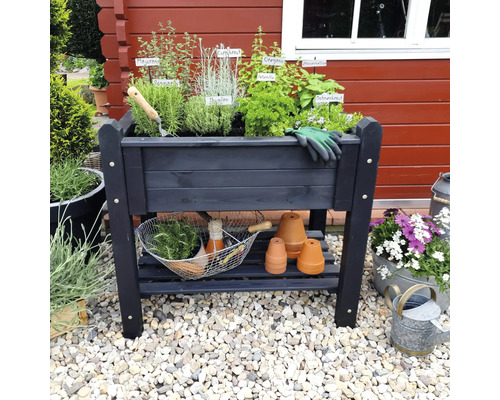 Jardinière sur pieds en bois avec herbes aromatiques, outils de jardinage et pots en terre cuite sur sol en gravier