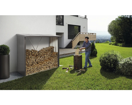 Étagère de rangement pour bois de chauffage dans le jardin avec un homme coupant du bois