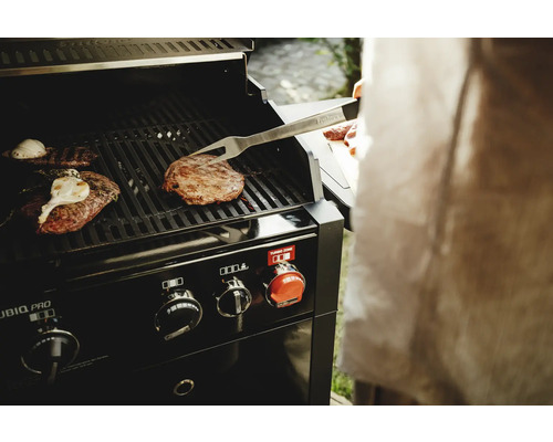 Grill mit Grillgut und Person mit Grillzange