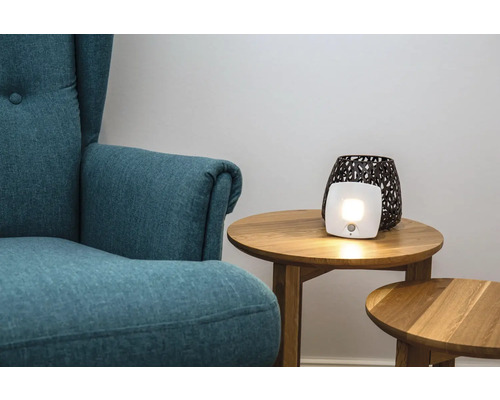 Salon avec fauteuil et lampe de luminothérapie sur une table d'appoint