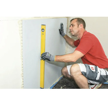 Mann richt eng Wandplack mat enger Wasserwaasser aus.