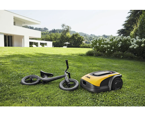 Ein Rasenmähroboter und ein Laufrad liegen auf einer Rasenfläche