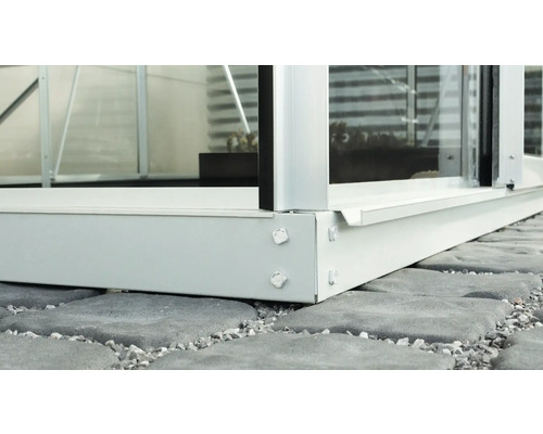 Gros plan sur la base d''une serre en aluminium sur des dalles de pierre.