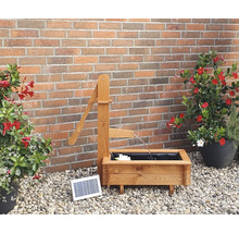 Gartenszene mit hölzernem Brunnen mit Solarpumpe und Pflanzgefäßen vor einer Backsteinmauer
