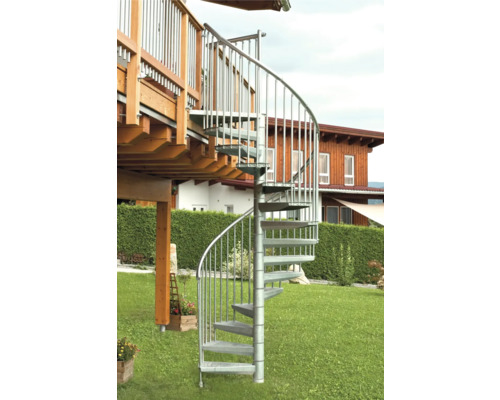 Eine Wendeltreppe aus Metall führt von einer Terrasse in einen Garten.