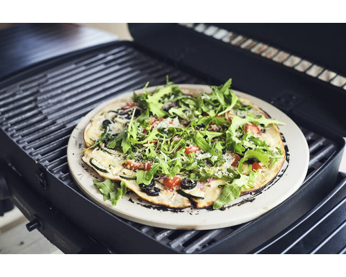 Pizza sur une pierre à pizza sur un barbecue