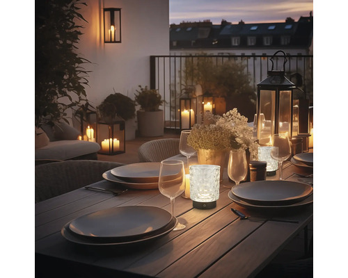 Table à manger décorée à l''extérieur avec de la vaisselle, des verres et des lampes à piles créant une atmosphère chaleureuse.