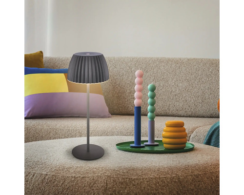Lampe de table décorative à côté de bougies et de coussins sur une table