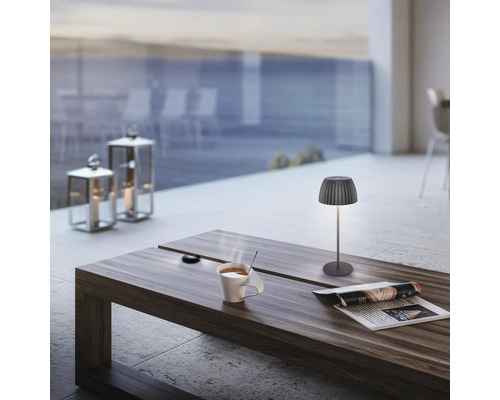 Ambiance chaleureuse avec lampe de table, lanternes à bougies et tasse de café sur une table en bois