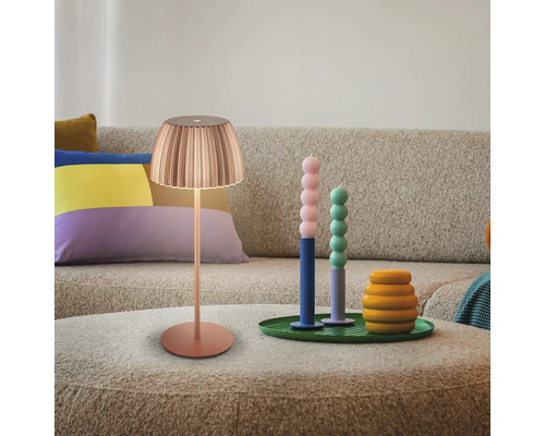 Scène avec lampe, bougies et articles de décoration sur une table devant un canapé.