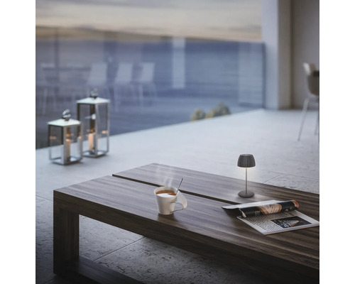 Scène avec lampe de table, tasse, journal et photophores sur une table à l''extérieur