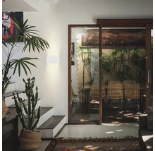 Intérieur avec plantes, escalier et coin repas derrière une porte coulissante en verre.