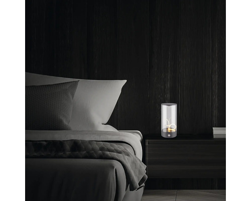 Nachttischlampe auf Nachttisch neben einem Bett in einem Schlafzimmer.