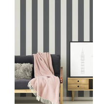 Scène avec papier peint rayé, canapé avec couverture, coussin et une gravure de Londres encadrée sur une table de chevet.