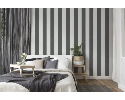 Chambre à coucher avec lit, table de chevet et papier peint rayé