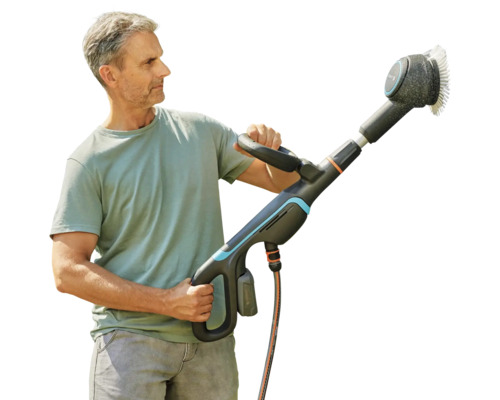 Un homme tient une brosse de nettoyage de surface Gardena.