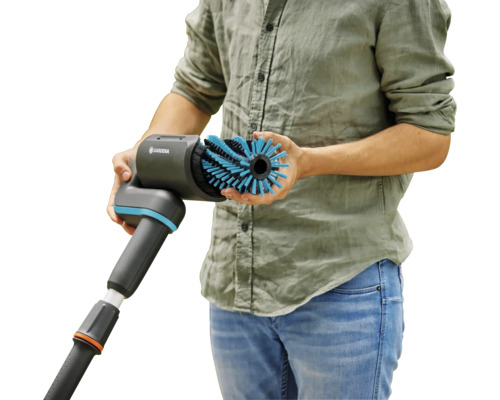 Un homme tient une brosse GARDENA avec raccordement d''eau dans sa main