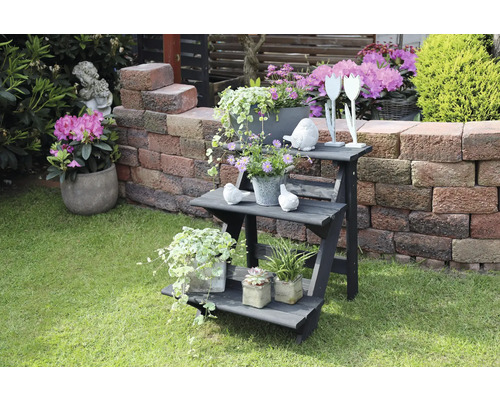 Dreistufige Pflanzenleiter aus Holz mit Pflanzgefäßen und Gartendekoration auf Rasen