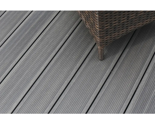 Gros plan sur des lames de terrasse en bois gris avec un meuble