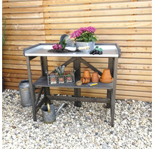 Gartentisch mit Arbeitsfläche, Blumen, Werkzeugen und Töpfen vor einem Holzzaun