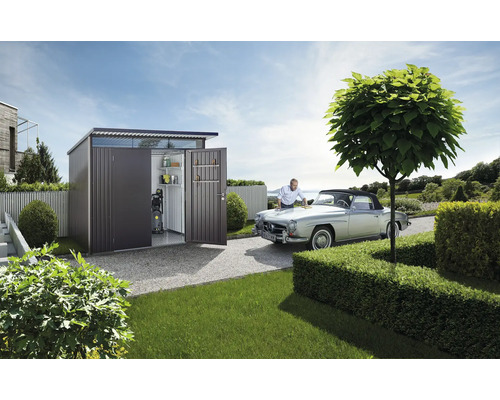 Gartenszene mit Gerätehaus, Oldtimer und Person bei der Autopflege