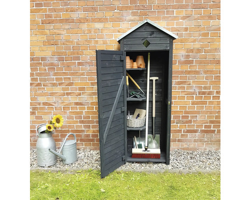 Armoire de jardin en bois avec outils de jardin et porte ouverte devant un mur de briques