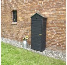 Armoire à outils en bois devant un mur de briques avec un bidon de lait et des tournesols.