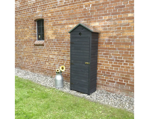 Armoire à outils en bois devant un mur de briques avec un bidon de lait et des tournesols.