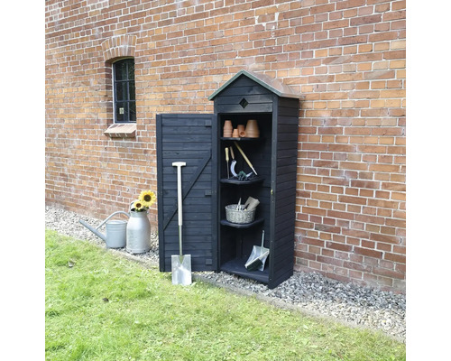 Armoire de jardin en bois avec outils de jardin devant un mur de briques