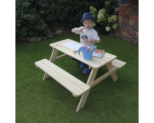 Kind an Picknicktisch aus Holz beim Malen im Garten