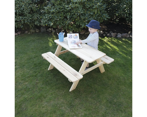 Kind liest Buch an einem Picknicktisch für Kinder im Garten.