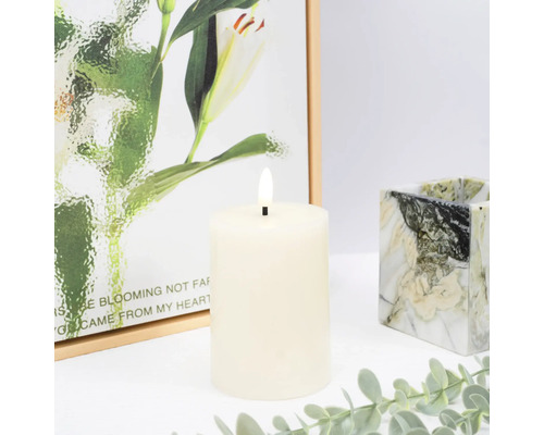 Dekorative LED Stumpenkerze mit Gemälde im Hintergrund und einem marmorierten Kerzenhalter.