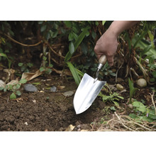 Jardinier plantant avec une plantoir dans le jardin.