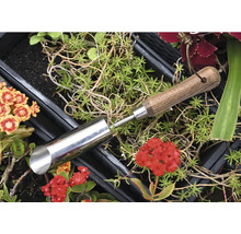 Pflanzlochbohrer aus Metall mit Holzgriff zwischen Pflanzen