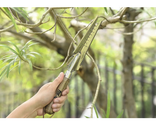 Une main tient un outil de jardin multifonctionnel avec un manche en bois