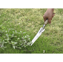 Gros plan d''une main tenant un désherbeur dans l''herbe