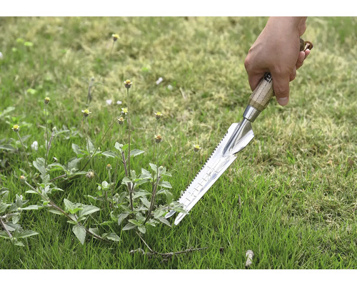 Gros plan d''une main tenant un désherbeur dans l''herbe